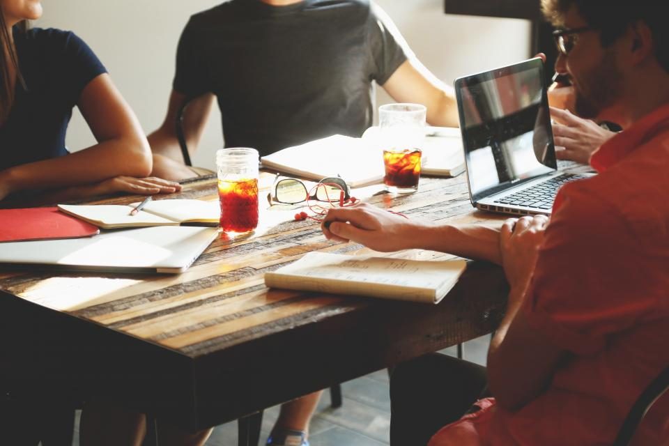 Team arbeitet gemeinsam an einem Tisch mit Laptops und Notizen